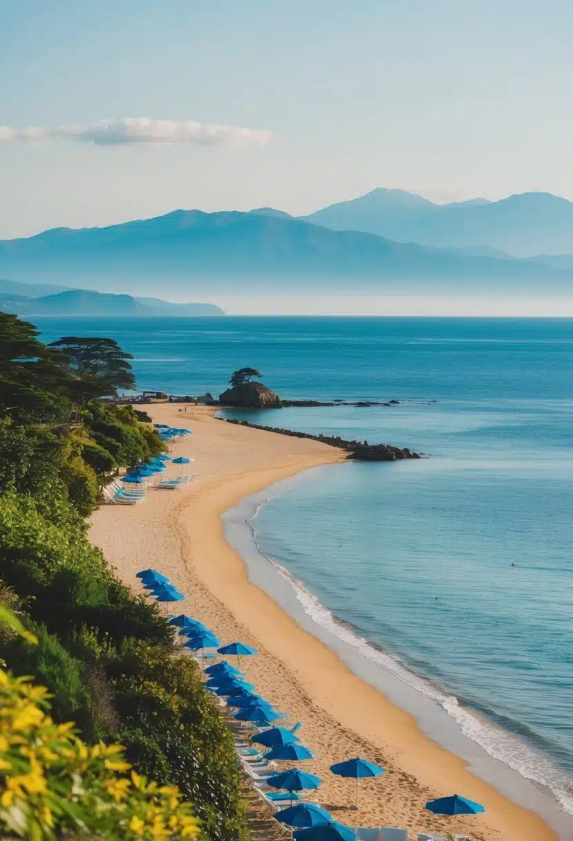 A serene Japanese beach with golden sand, clear blue waters, and lush greenery lining the shore. Sun umbrellas and beach chairs dot the coastline, with distant mountains in the background